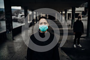 Person wearing a protective mask to prevent contagious disease spread.Life during epidemic/pandemic.Two people in abandoned place