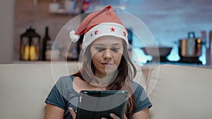 Person wearing santa hat and working on digital tablet