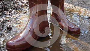 A person wearing wellington boots and stomping in a puddle