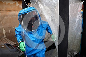 Person wears blue Personal protective equipment (PPE) with gas mask for protection from air pollution and biohazard