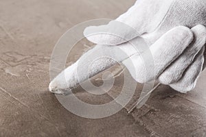 Person in white glove checking cleanliness of beige table, closeup