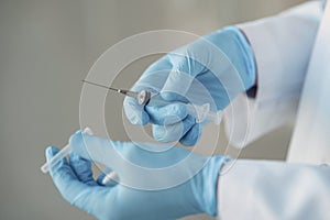 Person in a white uniform holding a syringe in her hands