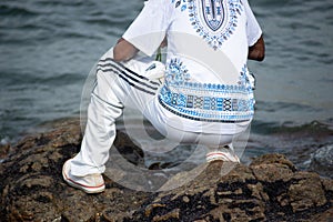 A person who is a fan of candomble, on top of the rocks, paying homage to iemanja on Rio Vermelho beach, city of Salvador, Bahia