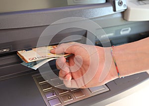 person withdraws money in European banknotes from an ATM