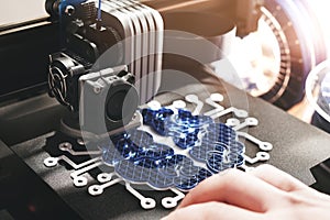 Person working on 3d printer making brain sculpture from blue and white plastic.