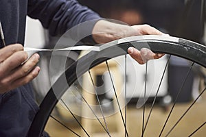 Person working on a bike painting, removing the masking tape of the wheel rim