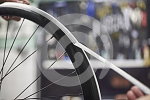 Person working on a bike painting, removing the masking tape of the wheel rim