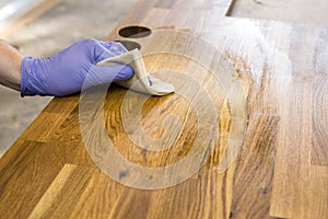 Person working  rubbing oiling with linseed oil natural wooden kitchen countertop before using. Solid wood butcher block.