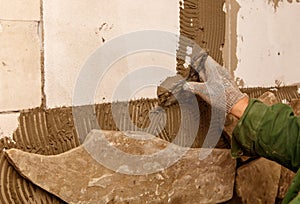A person is working on a wall, using a trowel to apply a layer of plaster