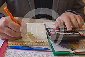 Person writing goals on a paper, writing business plan at workplace, man holding pens, papers, notes in documents, Saving money