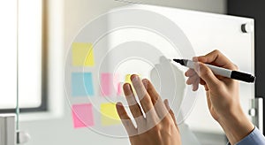 Person Writing on Transparent Whiteboard with Sticky Notes