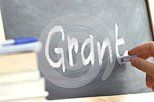 A person writing the word Grant on a blackboard.