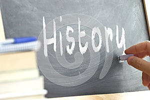 A person writing the word History on a blackboard. photo