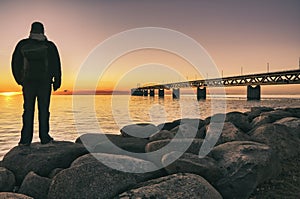 person at Ã¶resund bridge at sunset between sweden and denmark