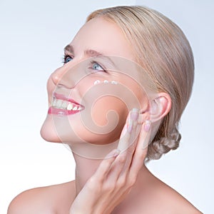 Personable woman applying moisturizer cream on her face for perfect skin