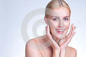 Personable woman applying moisturizer cream on her face for perfect skin