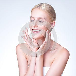 Personable woman applying moisturizer cream on her face for perfect skin