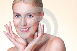 Personable woman applying moisturizer cream on her face for perfect skin