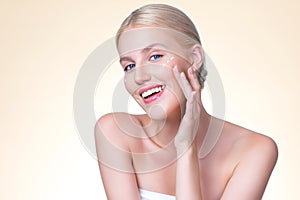 Personable woman applying moisturizer cream on her face for perfect skin