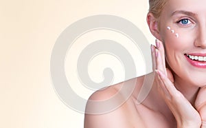 Personable woman applying moisturizer cream on her face for perfect skin