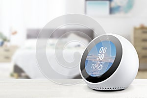 Personal assistant alarmclock and loudspeaker on a white wooden shelf of a smart home bedroom. Empty copy space photo