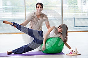 The personal coach helping woman in gym with stability ball