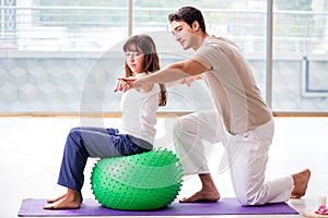 The personal coach helping woman in gym with stability ball