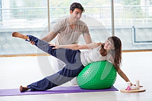 The personal coach helping woman in gym with stability ball