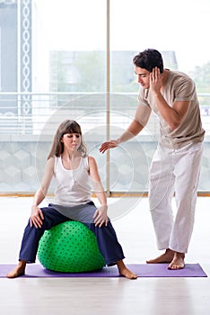 The personal coach helping woman in gym with stability ball