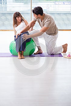 The personal coach helping woman in gym with stability ball