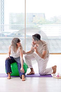 The personal coach helping woman in gym with stability ball