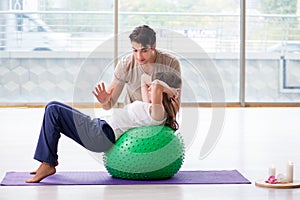 The personal coach helping woman in gym with stability ball