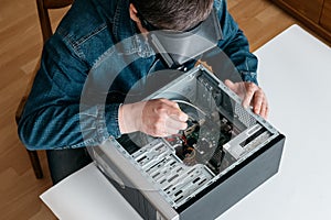 Personal computer repairing service, professional technician with magnifying glasses and screwdriver repairing broken pc desktop c photo