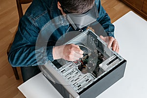 Personal computer repairing service, professional technician with magnifying glasses and screwdriver repairing broken pc desktop c