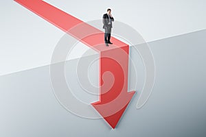 Personal crisis and business decline concept with confused businessman on red falling down arrow with abstract backdrop