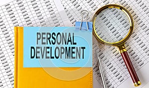PERSONAL DEVELOPMENT text on sticker on notebook with magnifier and chart. Business concept