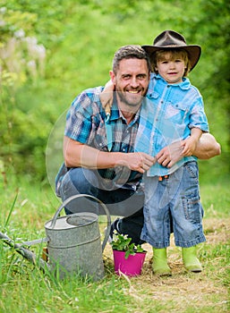 Personal example. Little helper in garden. Planting flowers. Growing plants. Take care of plants. Boy and father in