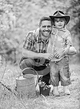 Personal example. Little helper in garden. Planting flowers. Growing plants. Take care of plants. Boy and father in