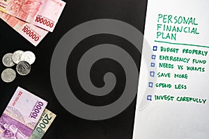 Personal financial plan checklist and Indonesian Rupiah money and coins with empty negative copy space background wallpaper