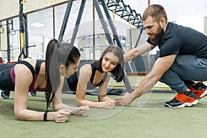 Personal fitness trainer coaching and helping client woman making exercise in gym. Sport, teamwork, training, people concept