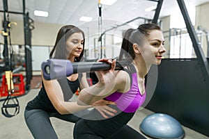 Personal fitness trainer coaching and helping client woman making exercise with weight in gym. Fitness, sport, training, people,