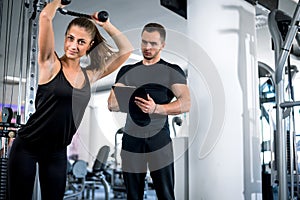 Personal fitness trainer with his client in gym.