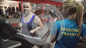 Personal fitness trainer motivating overweight girl during workout, high five