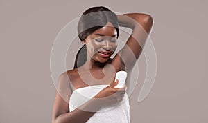 Personal Hygiene. Attractive Young Black Woman Applying Stick Deodorant To Armpit Zone