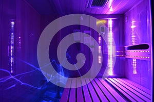 Personal infrared sauna illuminated by ultraviolet light