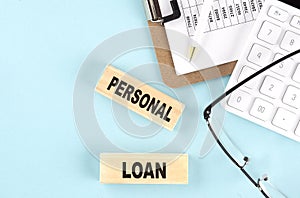 PERSONAL LOAN text written on wooden block with clipboard,eye glasses and calculator Business concept