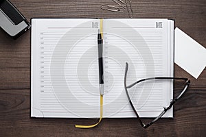 Personal organizer and pen with glasses on the table