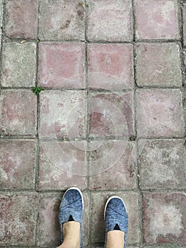 Personal point high angle view of wet gray shoes on red squre brick floor