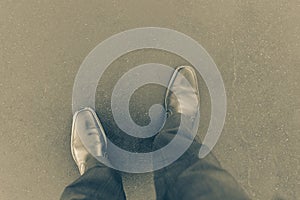 Personal point of view downward to pair of boots on concrete path in old-world split tone effect