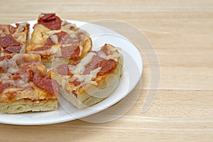 Personal size pepperoni pizza slices on a white plate